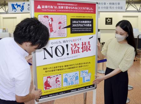 羽田空港第２ターミナルで盗撮禁止を訴えるポスターを掲示する全日空のスタッフ＝２０２３年７月