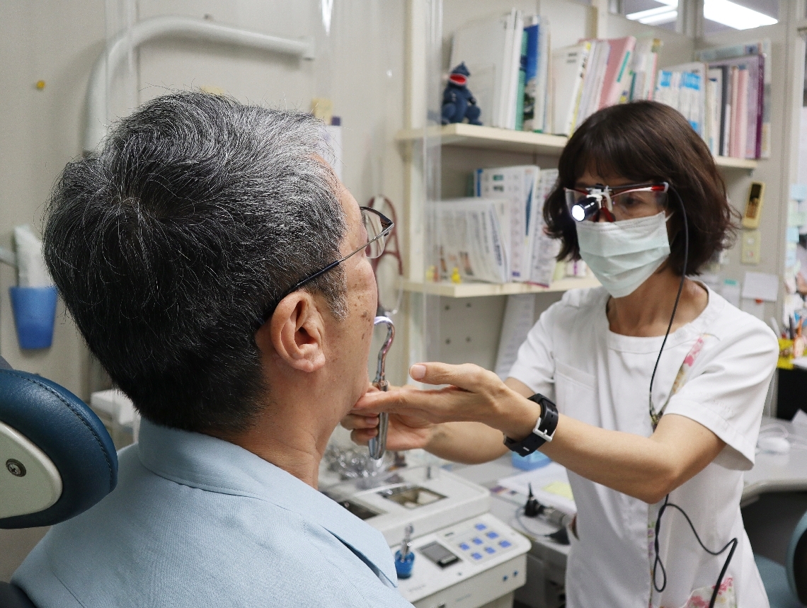 喉の痛みを訴える患者（左）を診察する医師＝２４日、大分市府内町の府内耳鼻咽喉科