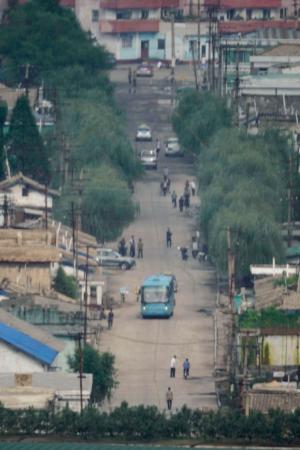 人や車が行き交う北朝鮮北西部新義州の中心部＝２日、中国・丹東から撮影（共同）