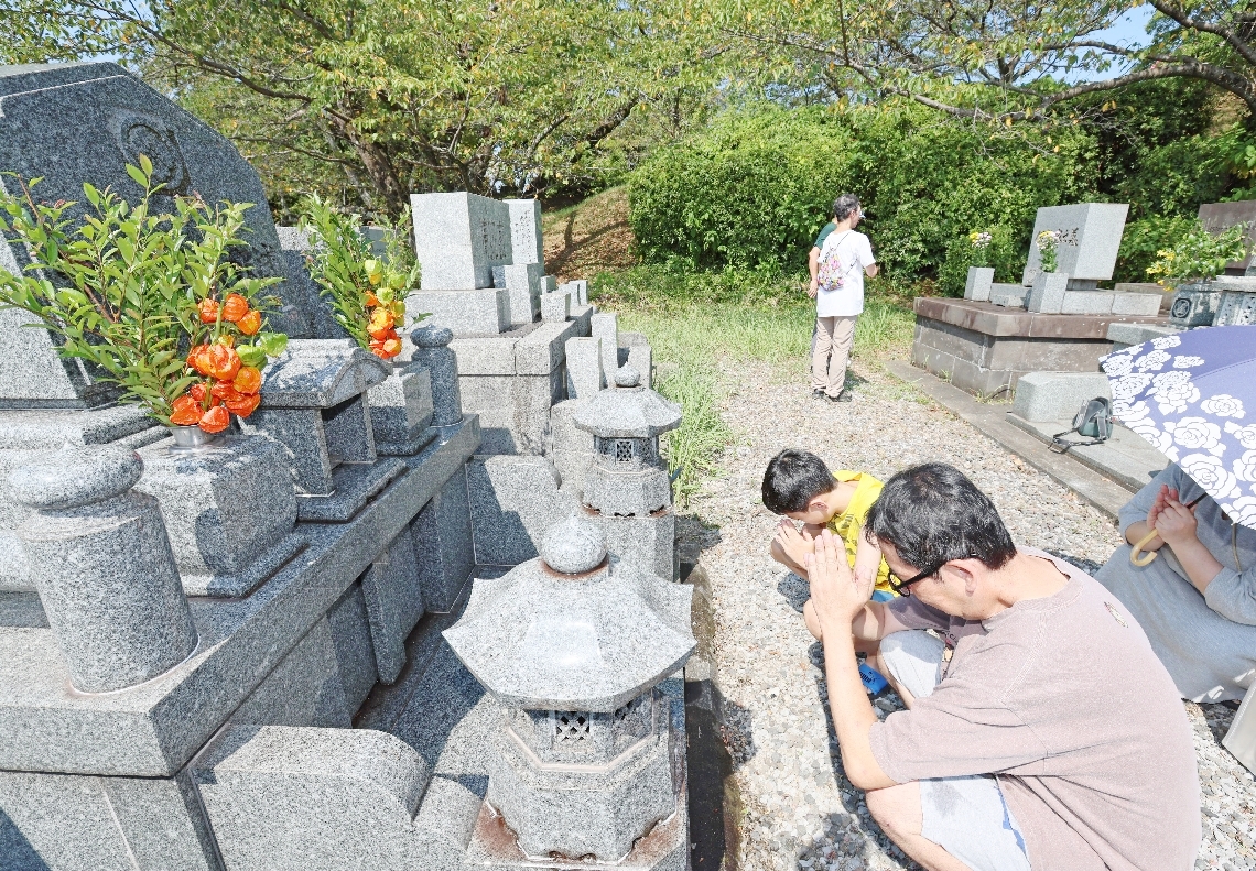 先祖の墓に参る家族連れ＝１３日、大分市永興の丸山墓地公園