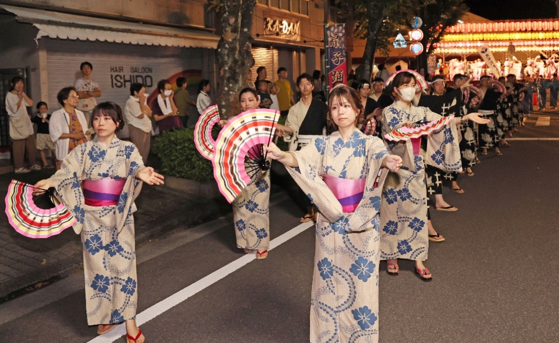 あでやかな扇子踊りを披露する参加者＝２４日、津久見市のＪＲ津久見駅前通り