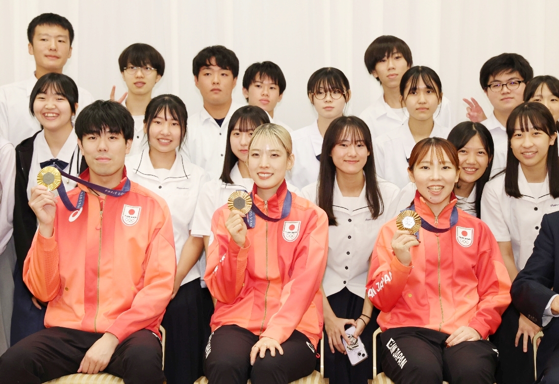 パリ五輪のフェンシング団体でメダルを獲得した（左から）敷根崇裕、江村美咲、上野優佳の県出身３選手が祝賀会に出席。高校生選手に囲まれ、メダルを手に晴れやかな笑顔を見せた＝２１日、大分市