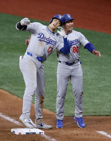 ３月、開幕戦のパドレス戦で適時打を放った大谷とヘルメットを合わせるドジャースのマッカラー一塁コーチ（右）＝ソウル（共同）