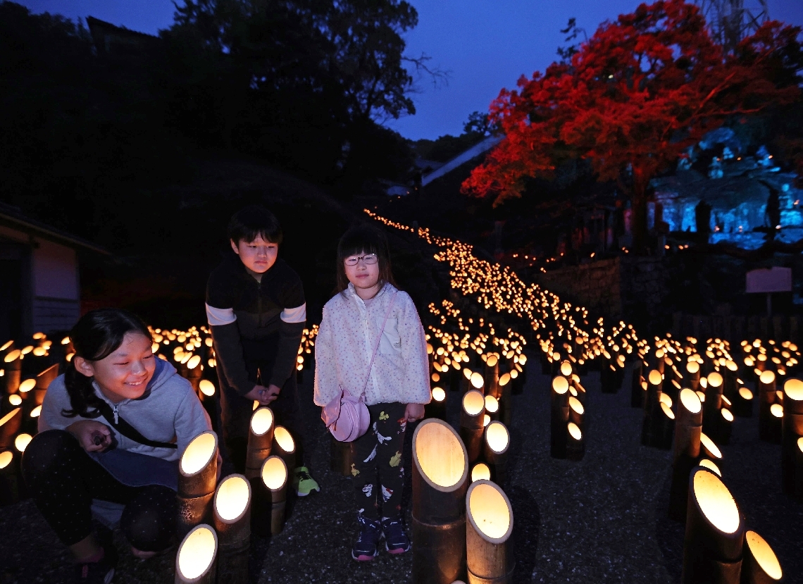 竹灯籠の中で揺らめく火を見つめる子どもたち＝１５日夕方、竹田市竹田の十六羅漢