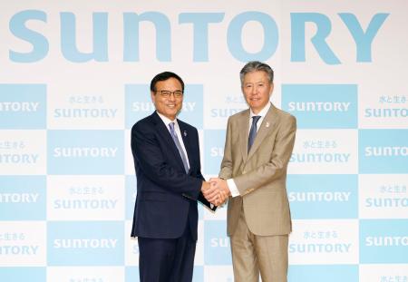 握手するサントリーＨＤの新浪剛史社長（左）と次期社長の鳥井信宏副社長＝１２日午後、東京都港区