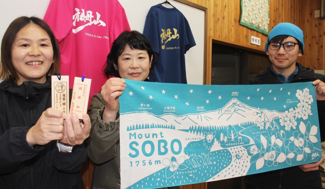 祖母山をイメージした手ぬぐいと登山手形をＰＲする祖母山麓自然・人共生空間整備プロジェクト実行委員会メンバーら＝竹田市神原の緒環