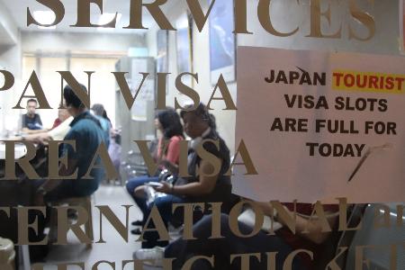 「きょうの日本向け観光ビザの申請枠は埋まりました」と書かれた旅行代理店の張り紙＝１６日、マニラ（共同）