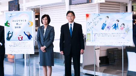 航空業界のカスハラ防止のため作成された啓発ポスター。左は日航の鳥取三津子社長＝２１日午前、羽田空港