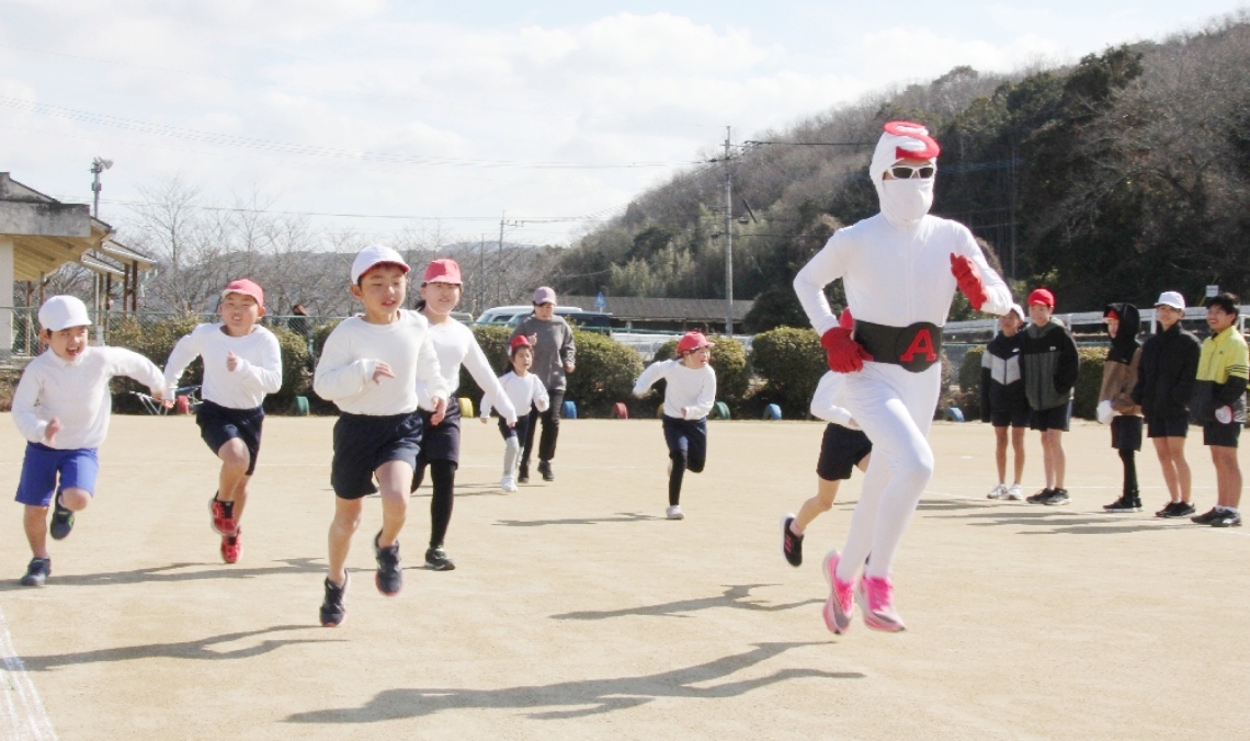 草地小の持久走大会で児童を先導して走る昭和仮面＝豊後高田市草地小