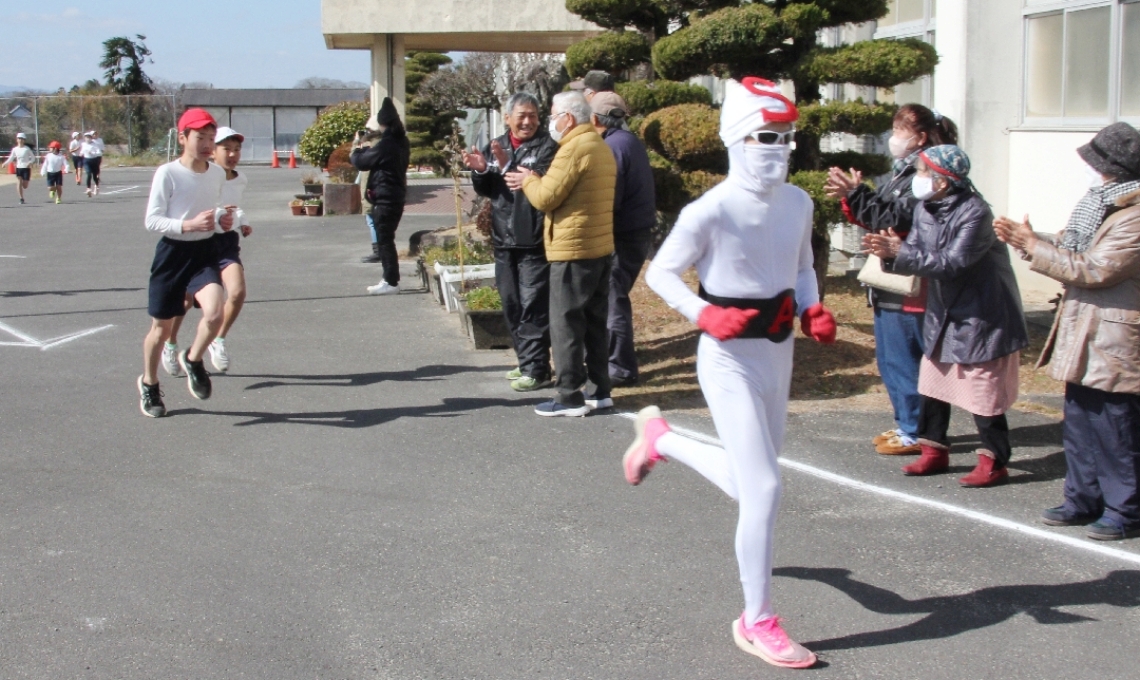 草地小の持久走大会で児童と一緒に走る昭和仮面