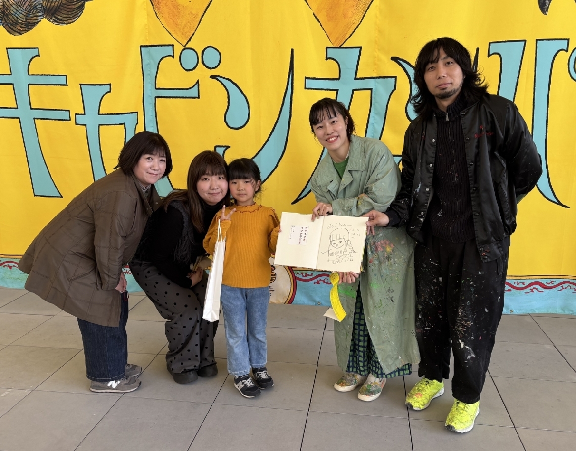 来場２万人目となった（左から）後藤美奈子さんと娘の吉野麻有さん、孫の葵湖ちゃんと、ザ・キャビンカンパニーの２人＝大分市寿町の県立美術館