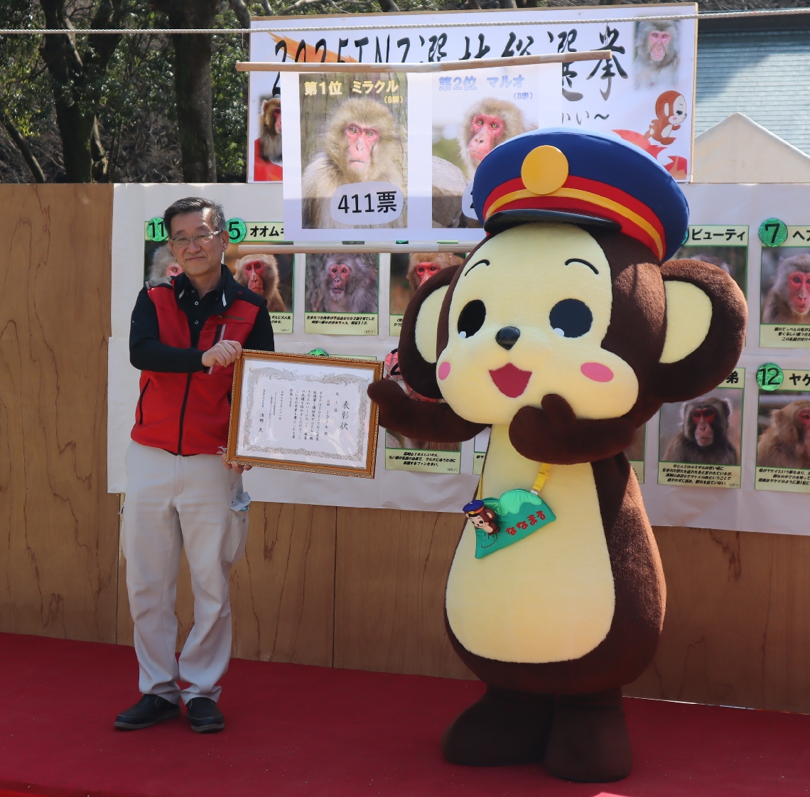 優勝したミラクルに代わって表彰状をもらい、観衆に手を振る着ぐるみ人形＝２２日、高崎山自然動物園