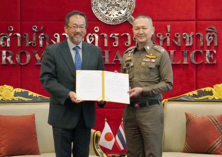 バンコクの警察本部で、タイ警察のタッチャイ人身売買対策センター長（右）に感謝状を手渡す日本の大鷹正人駐タイ大使＝２４日（共同）