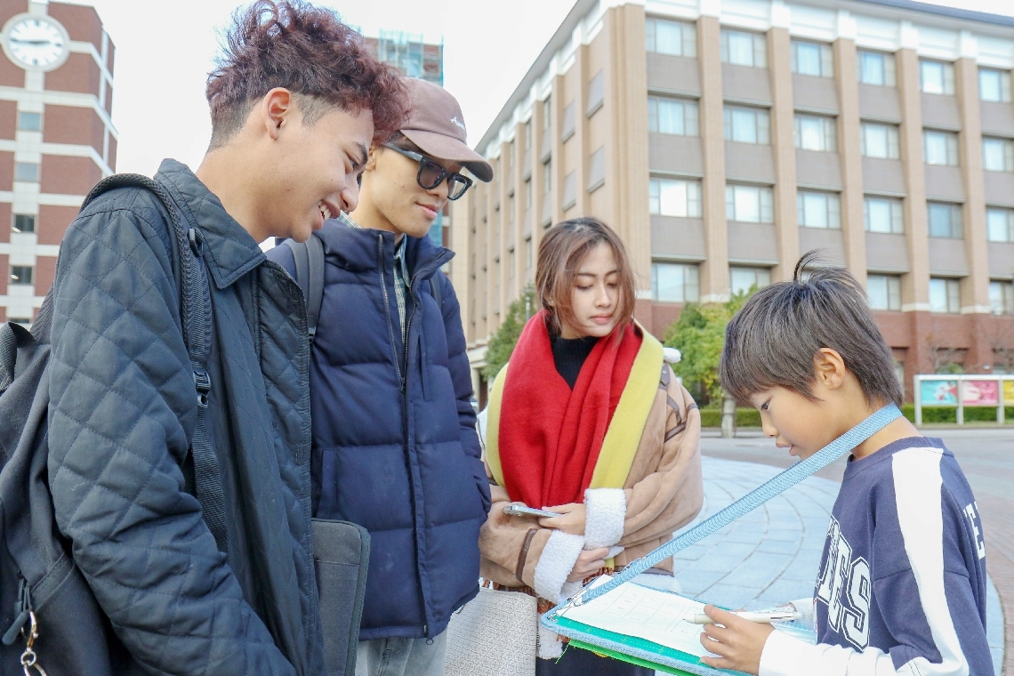 大学キャンパス内で留学生との英会話に挑戦する児童（右端）＝別府市の立命館アジア太平洋大