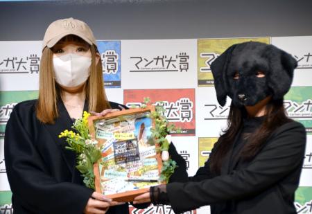 「マンガ大賞２０２５」で大賞に選ばれ、昨年の受賞者の泥ノ田犬彦さん（右）から記念品を受け取る売野機子さん＝２７日午後、東京都千代田区