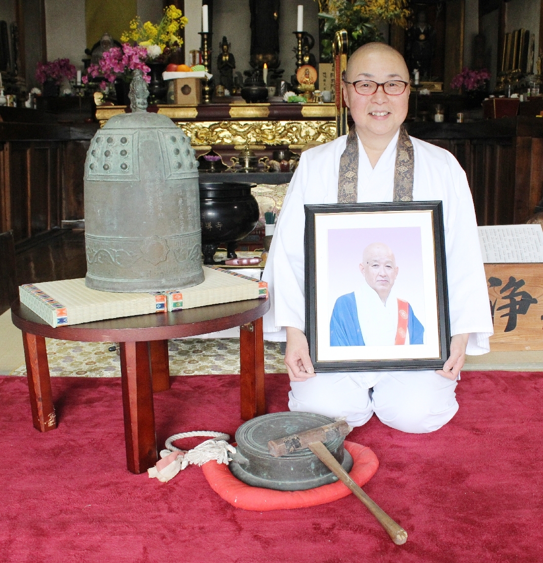 摩尼尊彦前住職の遺影を手に、半鐘の帰還を喜ぶ神月法嗣＝国東市国東町の興導寺