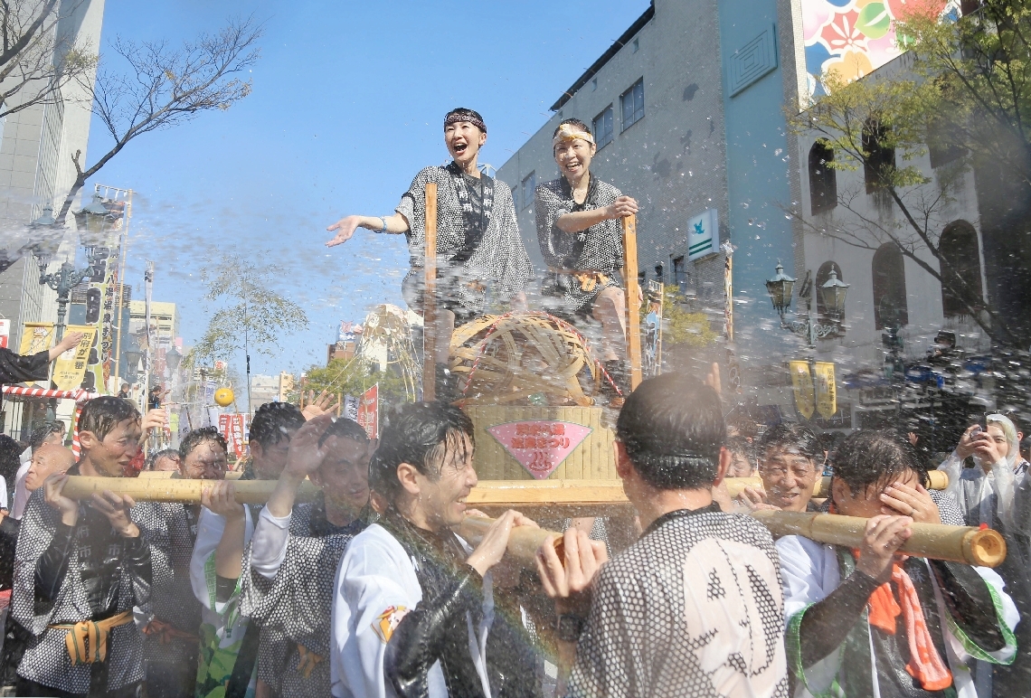 大量の温泉を浴びながら練り歩くみこし＝６日、別府市の別府駅前通り
