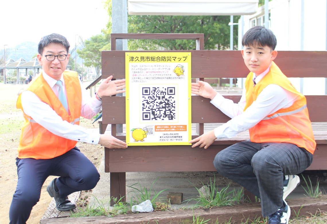 ウェブ版のＱＲコードを設置した石川正史市長と植田太陽さん（右）＝津久見市のつくみん公園