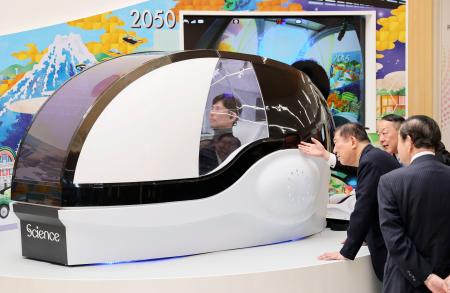 大阪ヘルスケアパビリオンで、「ミライ人間洗濯機」について説明を受ける石破首相（右から３人目）＝１２日午後、大阪市此花区の夢洲（代表撮影）