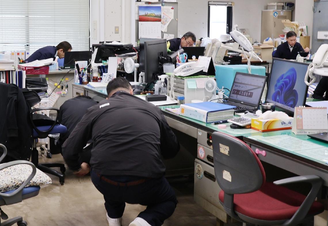 訓練のため机の下に避難しようとする由布市職員＝１６日、由布市役所本庁舎