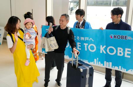 国際チャーター便の就航が始まった神戸空港に到着し、関係者の出迎えに笑顔を見せる乗客＝１８日午前