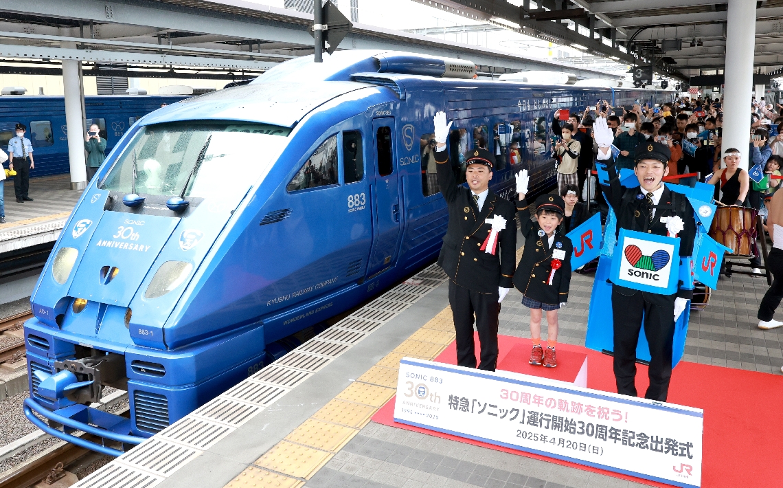 末藤隆浩駅長（手前左）らの合図で出発する特急ソニックの記念車両＝大分市のＪＲ大分駅