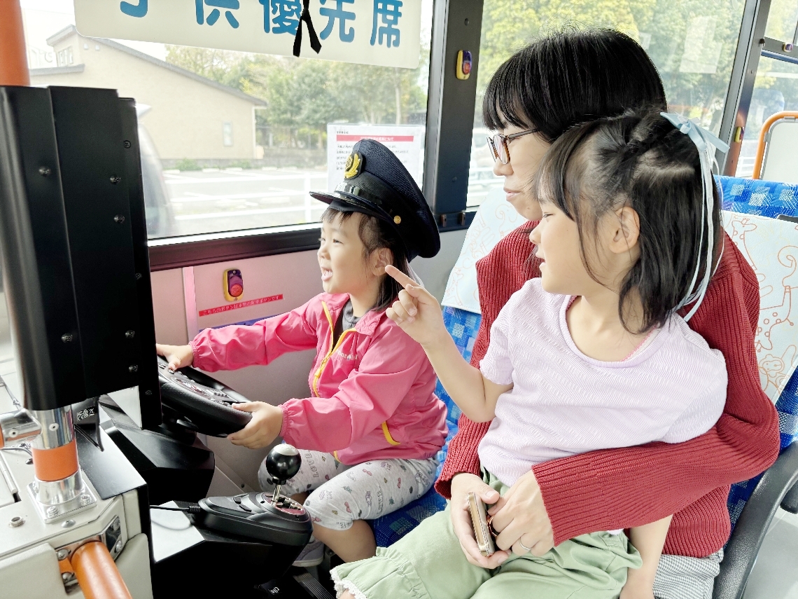 帽子をかぶり、ハンドルを握って運転手気分＝別府市