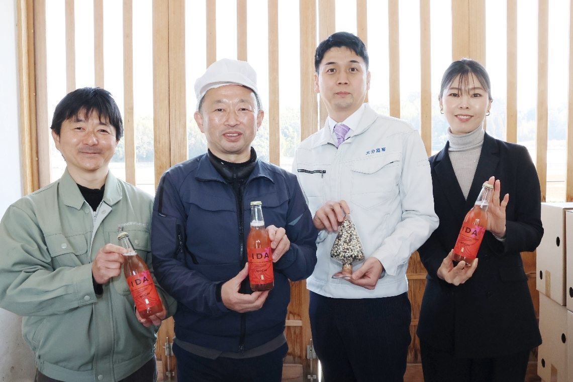 もちとうきびを使ったクラフトビールを手にする藤居淳一郎社長（左から２人目）、大分高専の森田昌孝准教授（右から２人目）ら