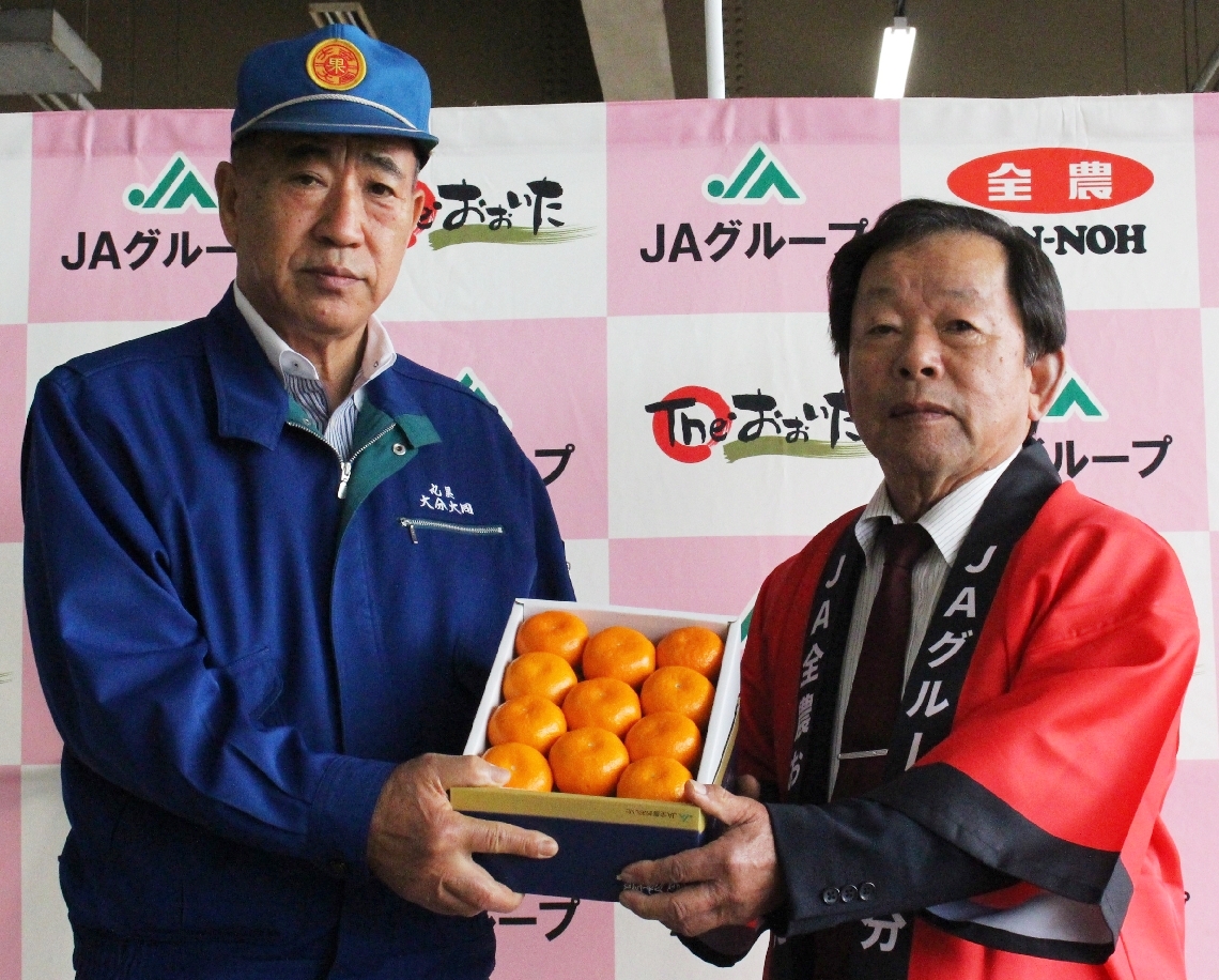 初競り式でハウスミカンをＰＲする木村房雄会長（右）＝２５日、大分市公設地方卸売市場