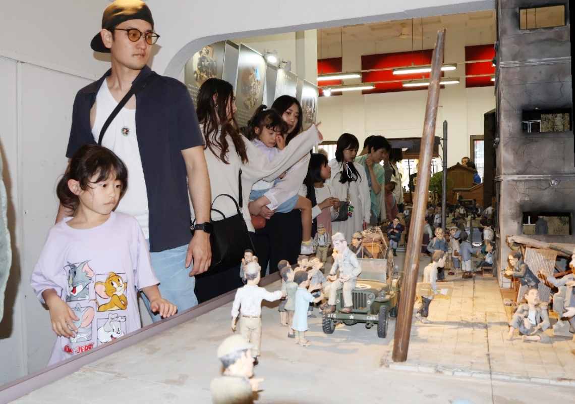 昭和２０～３０年代を再現したジオラマに見入る来館者＝豊後高田市中央通り商店街の昭和の町展示館