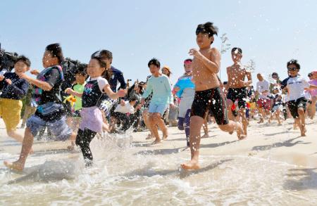 和歌山県白浜町の白良浜が海開きし、一斉に海へ駆け込む海水浴客＝３日午前