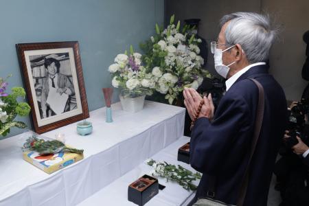 朝日新聞阪神支局に掲げられた小尻知博記者の遺影の前で、手を合わせる男性＝３日午前、兵庫県西宮市