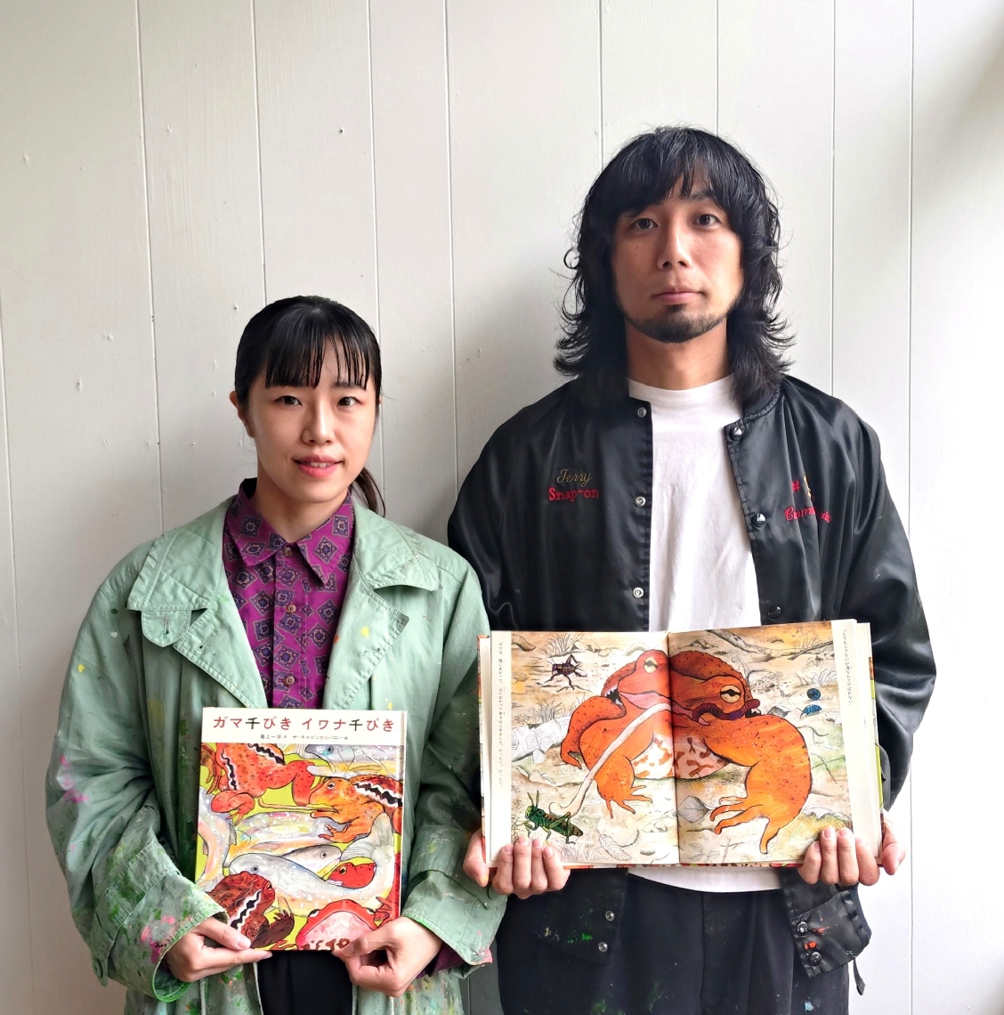 「ガマ千びき　イワナ千びき」を手にする、ザ・キャビンカンパニーの阿部健太朗さん（右）と吉岡紗希さん