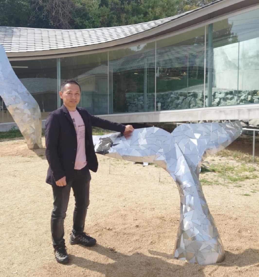 会場に展示した「クジラの尾びれ」と芝田知明さん＝高松市の屋島山上交流拠点施設やしまーる