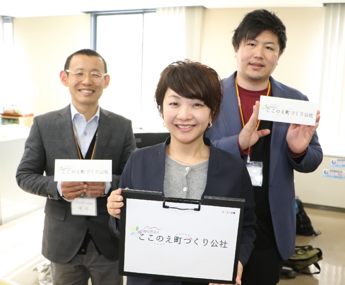 手作りのロゴマークを手に、「九重町観光を後押しします」と意気込むここのえ町づくり公社の事務局スタッフ＝九重町役場