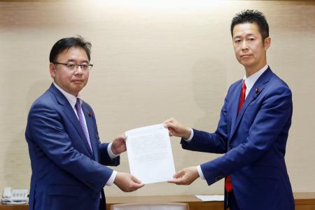 自民党の上野賢一郎与党筆頭理事（左）に年金制度改革法案の修正案を手渡す野党筆頭理事を務める立憲民主党の井坂信彦氏＝２０日午後、国会