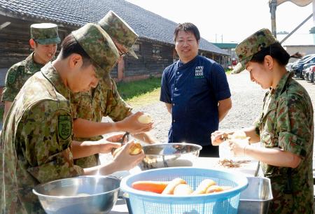 陸上自衛隊の炊事訓練で、隊員にアドバイスする冨成寿明さん（右から２人目）＝２８日午前、金沢市