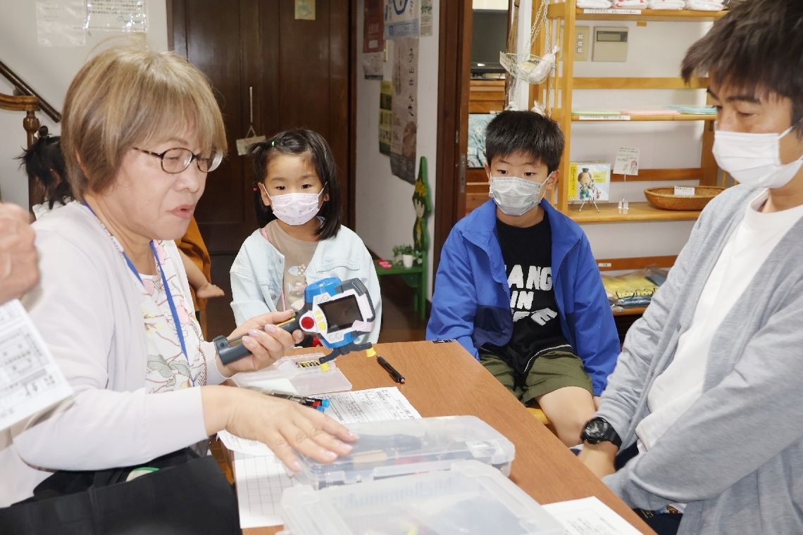 佐藤義美記念館で大分おもちゃ病院のドクターからおもちゃの“診察”を受ける子どもら＝竹田市竹田