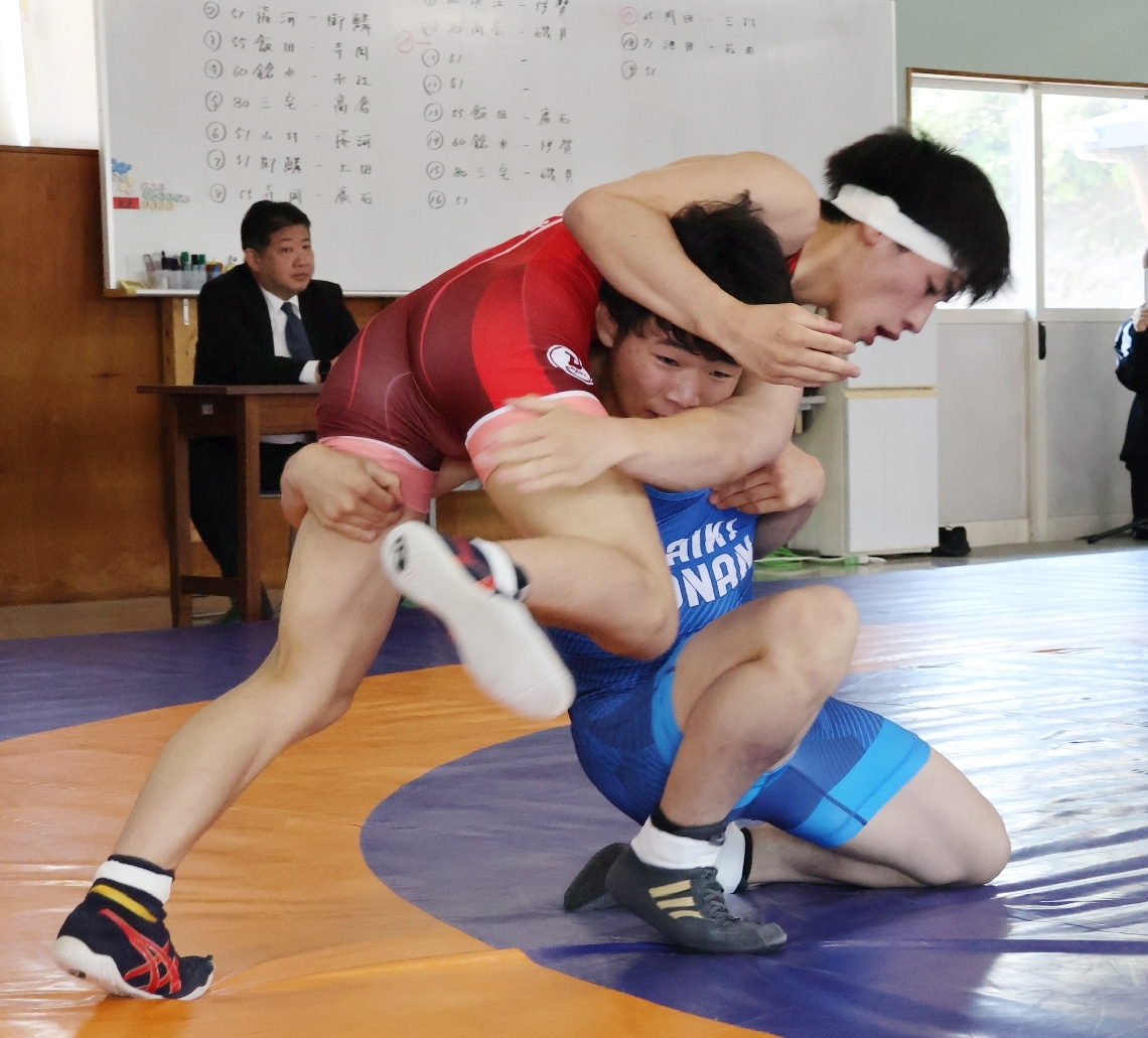 【レスリング男子学校対抗】６０キロ級でしのぎを削る文理大付の広石（赤）と豊南の鎗水＝佐伯市の文理大付高