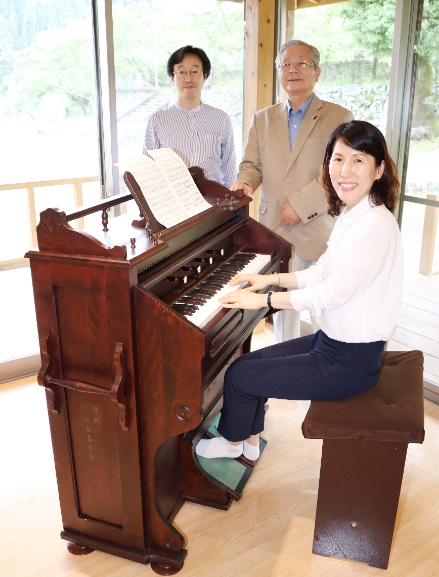リードオルガンの修復を喜ぶ金成妍館長（手前）と作業に当たった和久井真人さん（後列左）、氏家文高さん＝玖珠町森の久留島武彦記念館