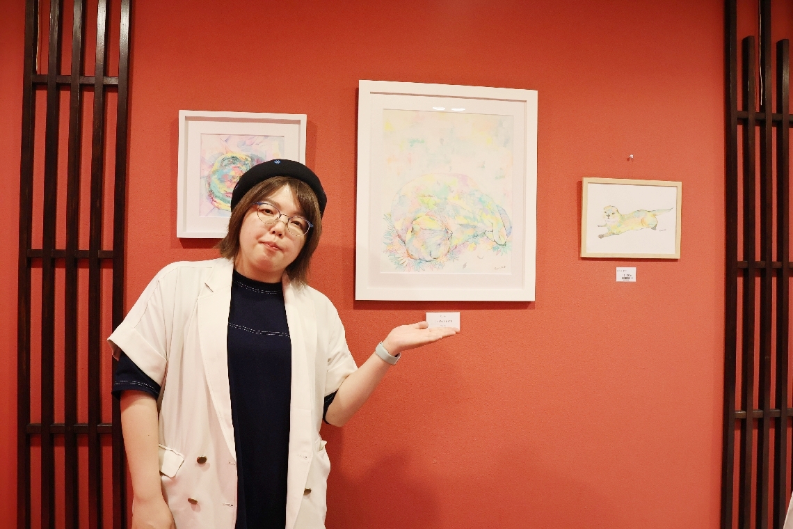 ギャラリーに絵画を展示するイラストレーターの秦ひとみさん＝別府市のホテル白菊