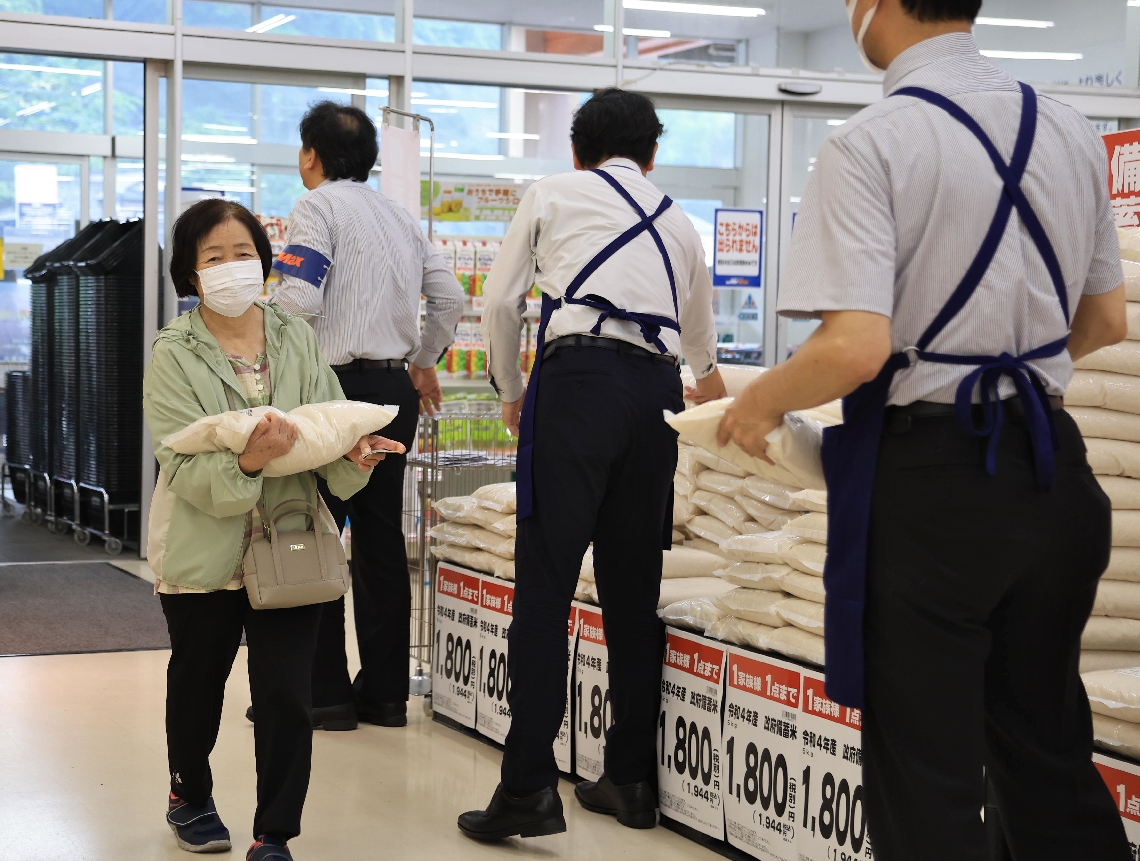 店員から備蓄米を受け取った買い物客＝１２日、大分市生石のミスターマックス西大分店