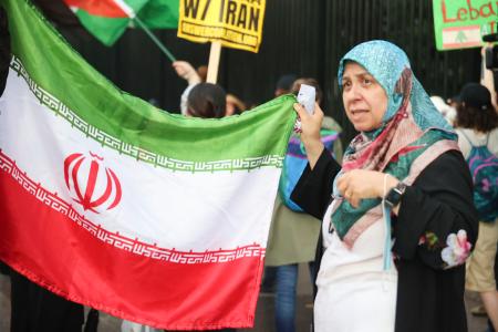 ワシントンのホワイトハウス前で行われた抗議デモで、イラン国旗を掲げるタヘルさん＝１８日（共同）