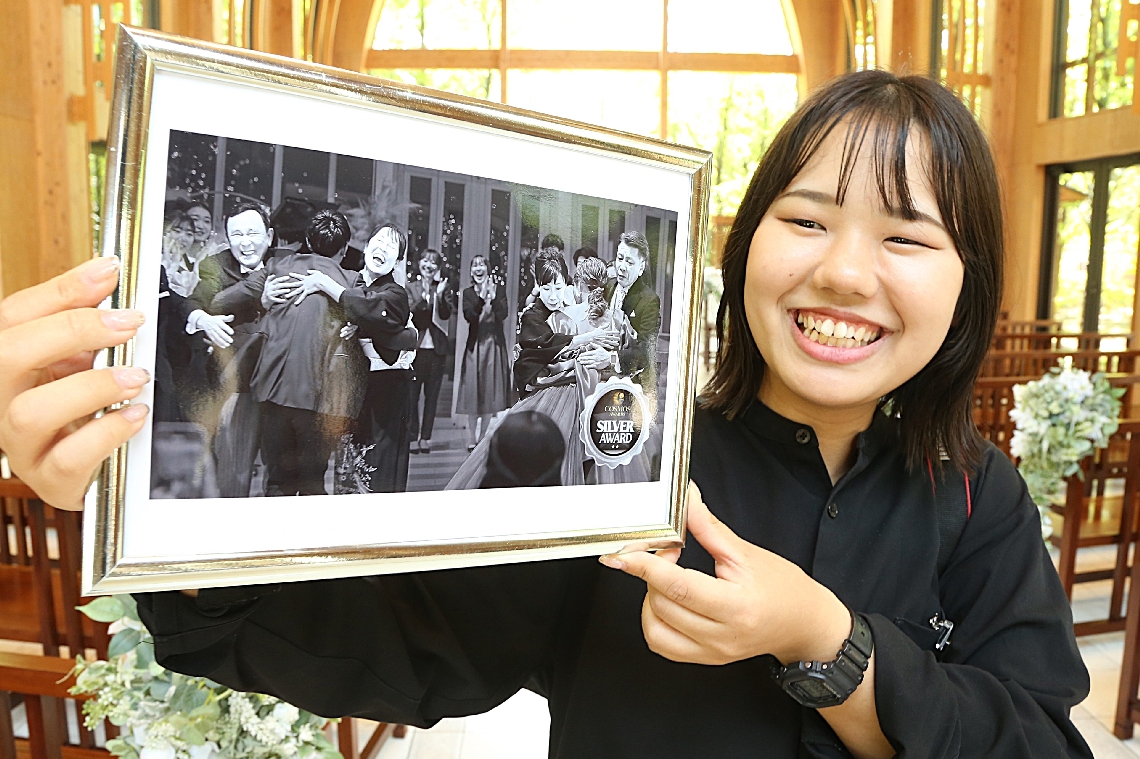 国際的な写真コンテスト「コスモスアワーズ」で銀賞に輝いた作品を掲げる西田佳奈さん＝大分市高江西のララシャンス迎賓館