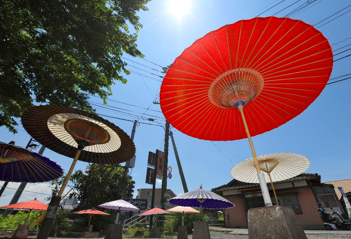 大分県は気象庁の統計上、最も早い６月中の梅雨明けとなった。からりと晴れた空の下で、天日干しされる和傘＝２７日、中津市鷹匠町