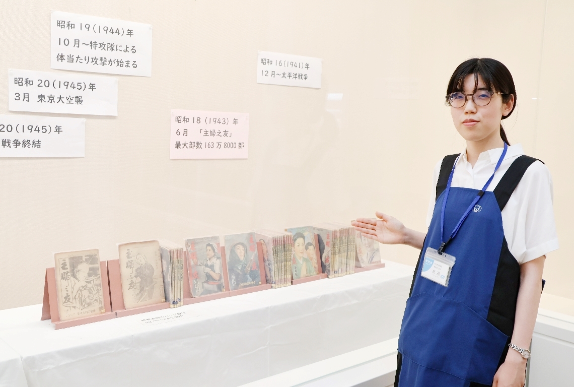 「雑誌の厚さからも戦争の影響が感じられる」と説明する司書の高原由紀さん＝宇佐市上田の市民図書館渡綱記念ギャラリー