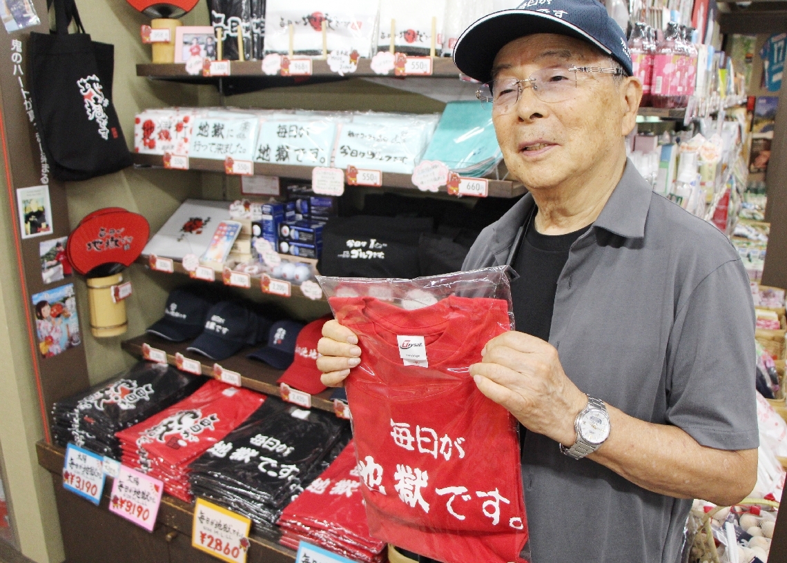 「毎日が地獄です」のＴシャツを手に「盗用がまかり通ったら困る」と訴える平塚明夫社長＝今月２日、別府市