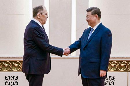 ロシアのラブロフ外相（左）と握手する中国の習近平国家主席＝１５日、北京（タス＝共同）