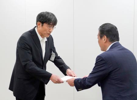 国交省九州運輸局からの改善を指示する文書を受け取る熊本市の井芹和哉交通事業管理者（左）＝１８日午後、福岡市