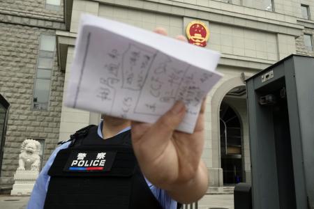 スパイ罪で起訴された日本人男性の判決公判が開かれた北京市の第２中級人民法院前で撮影を阻止する警察官＝１６日（共同）